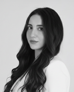 Grayscale portrait of Maria Frankian, a woman with long dark wavy hair, wearing a light blazer, looking slightly away from the camera.