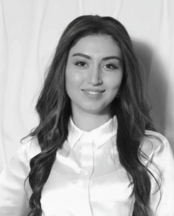 Headshot of Anush Manasyan, a woman with long dark hair, smiling gently while wearing a white collared shirt.