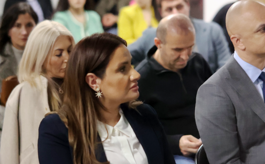 Professionals listening intently at a real estate legal seminar. A woman in a dark blazer and white shirt is in the foreground, wearing star earrings.